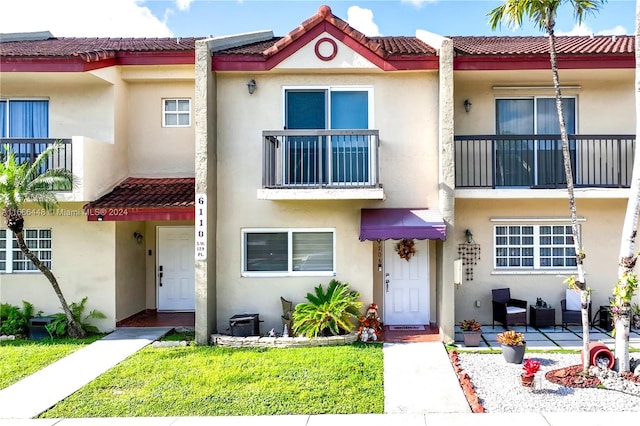 townhome / multi-family property with a patio, a front yard, and a balcony