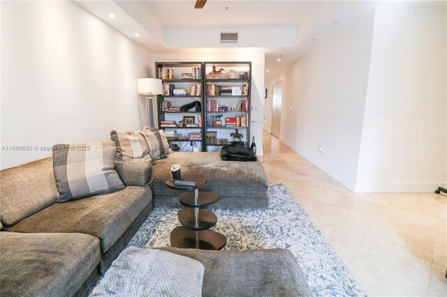 living room with ceiling fan and a tray ceiling