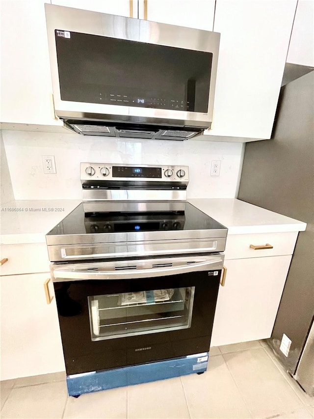 kitchen featuring white cabinetry, stainless steel appliances, and light tile patterned flooring