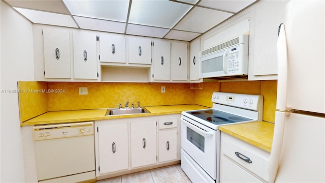 kitchen with white appliances, white cabinetry, sink, and a drop ceiling