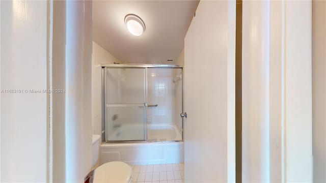 bathroom featuring toilet, enclosed tub / shower combo, and tile patterned floors