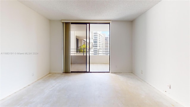 unfurnished room featuring a wall of windows and a textured ceiling