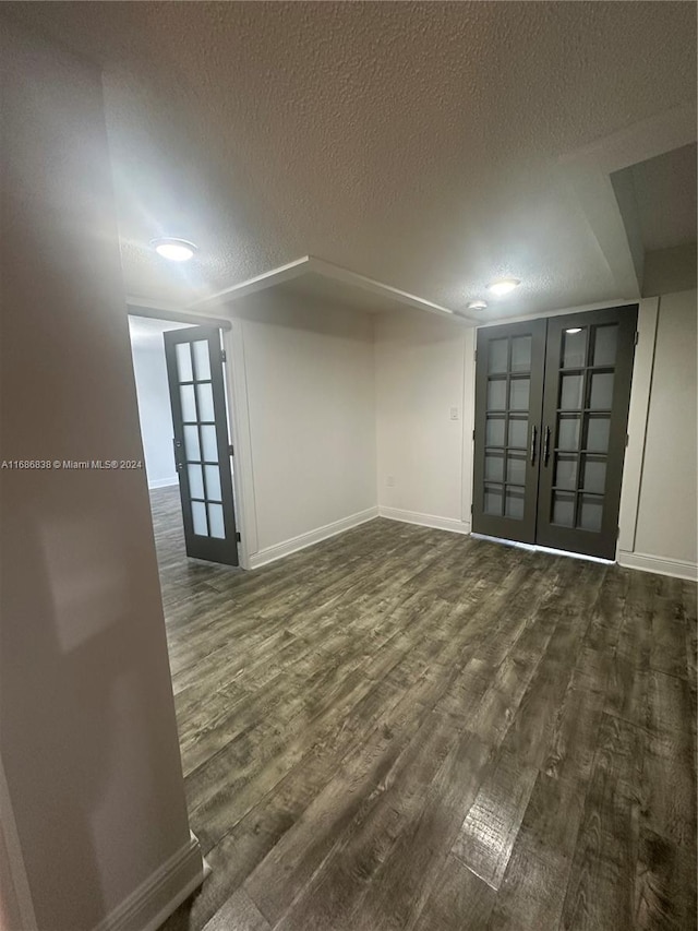 empty room featuring french doors, a textured ceiling, and dark wood-type flooring