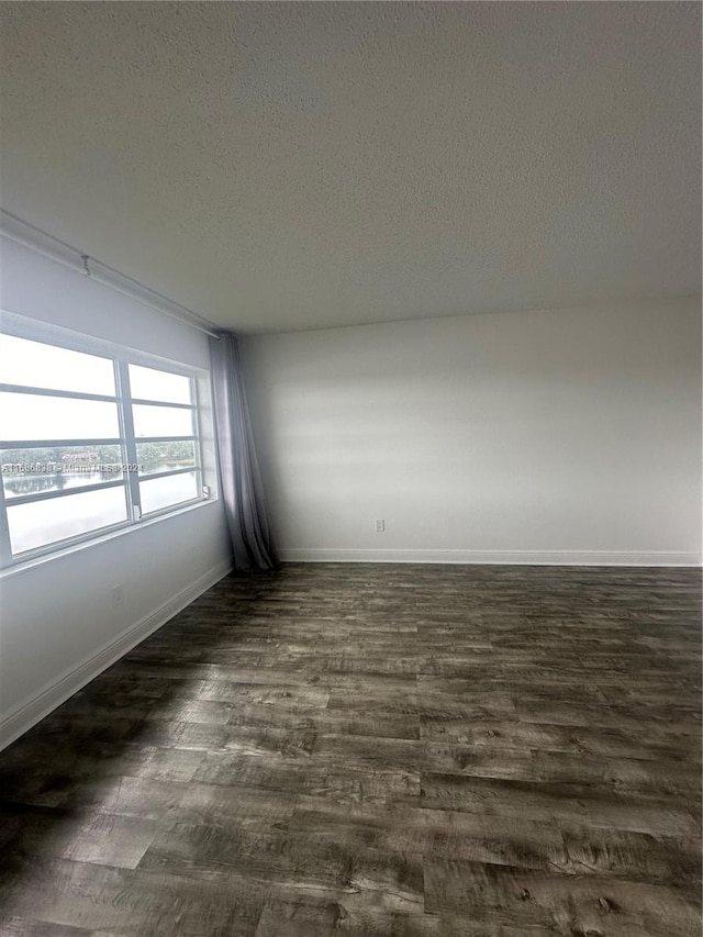 unfurnished room with a textured ceiling and dark hardwood / wood-style flooring