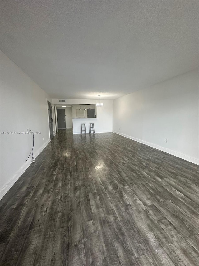 unfurnished living room featuring a textured ceiling and dark hardwood / wood-style flooring