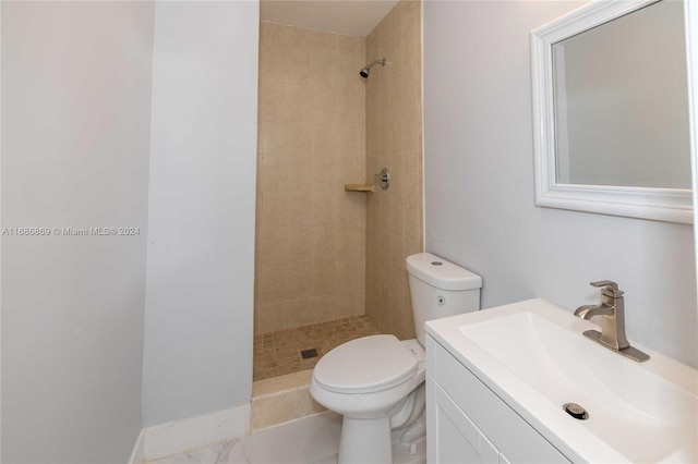 bathroom featuring a tile shower, vanity, and toilet