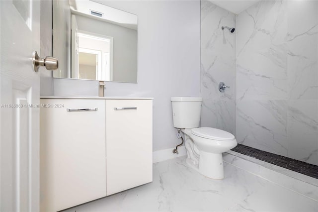 bathroom with tiled shower, vanity, and toilet