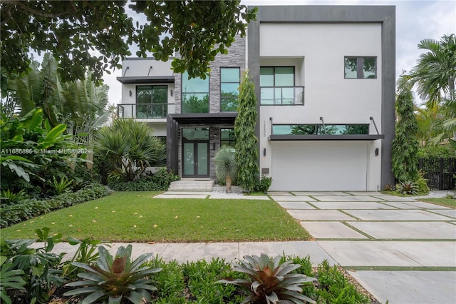 contemporary home with french doors, a balcony, a front yard, and a garage