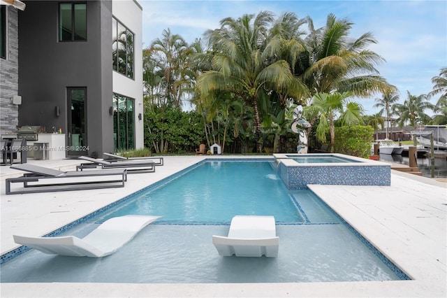 view of pool with a patio area, an in ground hot tub, area for grilling, and exterior kitchen