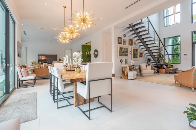 tiled dining area with a towering ceiling, a baseboard heating unit, and an inviting chandelier