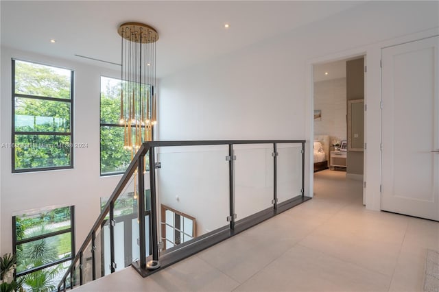 corridor featuring light tile patterned floors and a chandelier