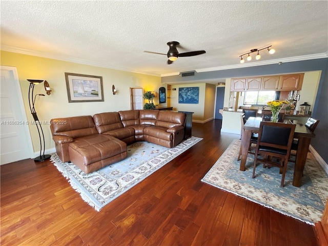 living room featuring ceiling fan, dark wood-type flooring, a textured ceiling, and crown molding