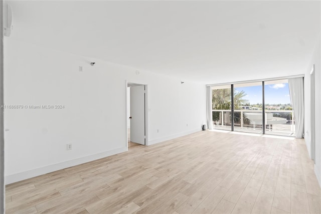 unfurnished room with expansive windows and light wood-type flooring