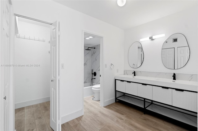 full bathroom featuring hardwood / wood-style floors, vanity, toilet, and tiled shower / bath