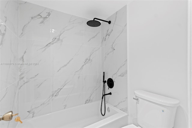 bathroom featuring toilet and tiled shower / bath