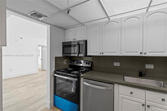 kitchen with stainless steel appliances, white cabinetry, light hardwood / wood-style floors, and sink