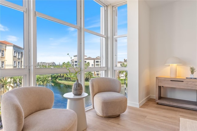 sitting room featuring baseboards, wood finished floors, and a water view