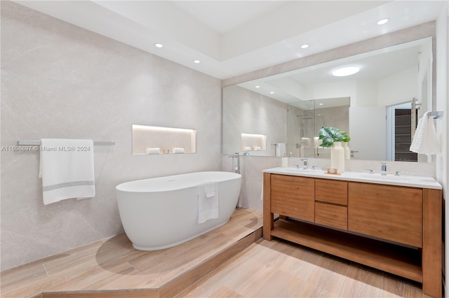 bathroom with wood-type flooring, vanity, and independent shower and bath