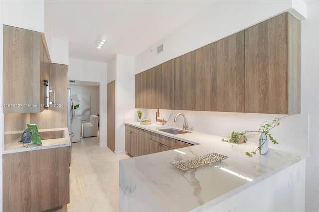 kitchen featuring brown cabinets, a sink, visible vents, stainless steel appliances, and modern cabinets