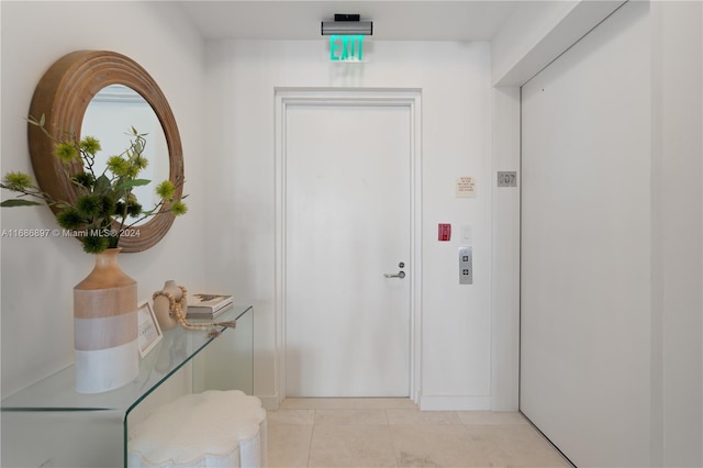 doorway with elevator and light tile patterned floors