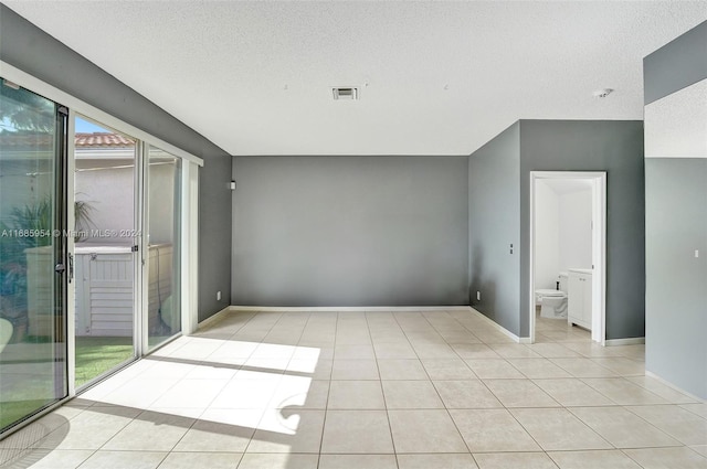 tiled empty room featuring a textured ceiling