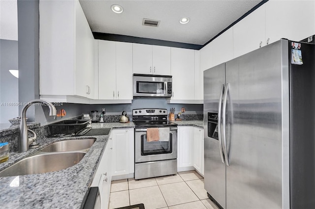 kitchen with dark stone counters, sink, white cabinets, appliances with stainless steel finishes, and a textured ceiling