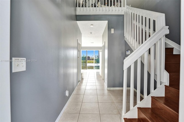 interior space featuring a towering ceiling, a textured ceiling, and light tile patterned floors