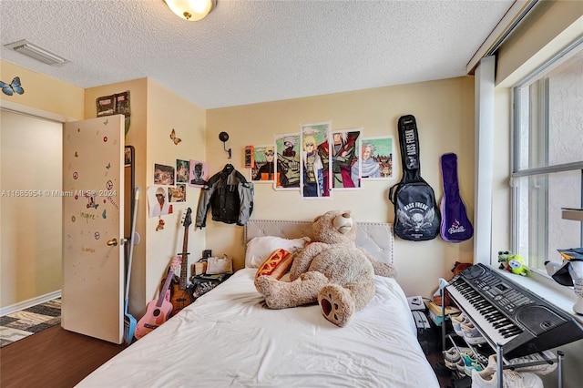 bedroom featuring dark wood-type flooring, multiple windows, and a textured ceiling