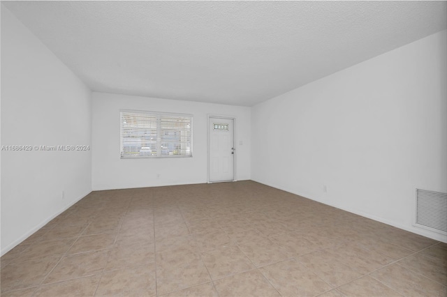 tiled spare room featuring a textured ceiling