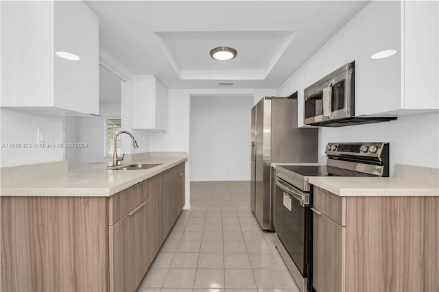 kitchen with sink, a raised ceiling, white cabinetry, light tile patterned floors, and appliances with stainless steel finishes