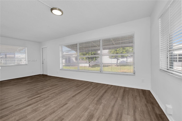 unfurnished room featuring a textured ceiling and dark hardwood / wood-style flooring