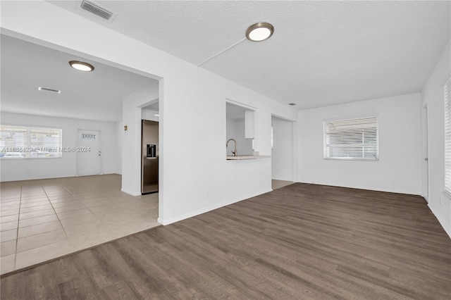 unfurnished living room featuring hardwood / wood-style flooring, a textured ceiling, and sink