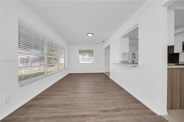 unfurnished living room with sink, wood-type flooring, and a textured ceiling