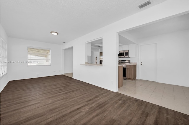 unfurnished living room featuring a textured ceiling and light wood-type flooring