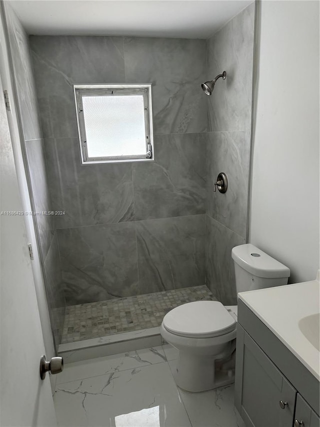 bathroom featuring vanity, tiled shower, and toilet