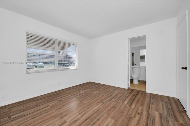 2851 W Golf Blvd, Pompano Beach, FL 33064 - unfurnished bedroom with wood finished floors, baseboards, and ensuite bathroom