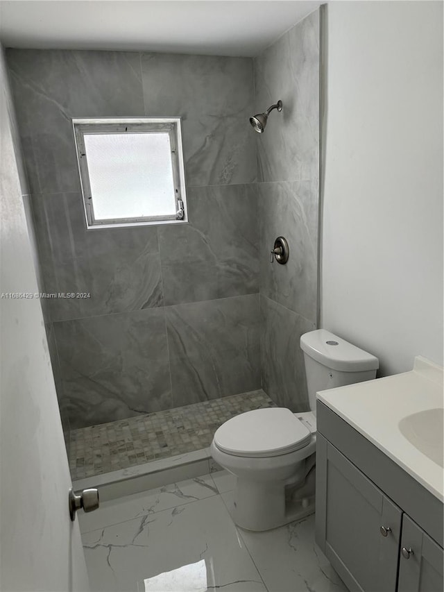 bathroom featuring toilet, vanity, and tiled shower