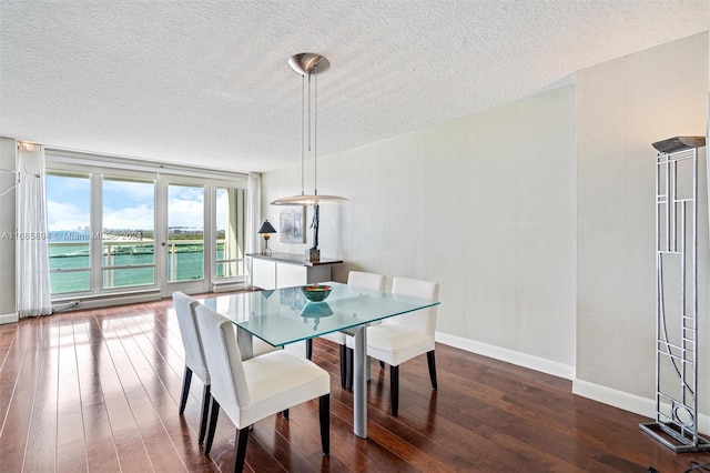 dining room with a water view, hardwood / wood-style flooring, and a textured ceiling