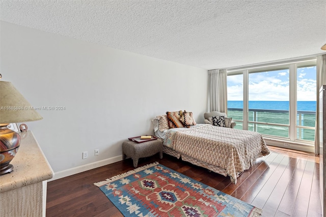 bedroom featuring dark hardwood / wood-style floors, a textured ceiling, and a water view