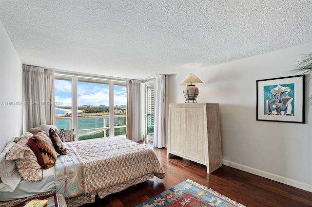 bedroom featuring a water view, a textured ceiling, and dark hardwood / wood-style flooring