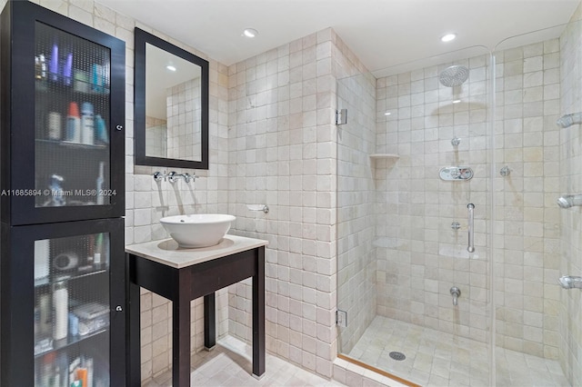 bathroom featuring tile patterned flooring, tile walls, sink, and a shower with shower door