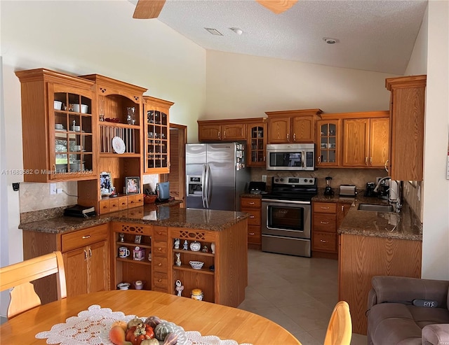 kitchen featuring tasteful backsplash, appliances with stainless steel finishes, a textured ceiling, high vaulted ceiling, and sink