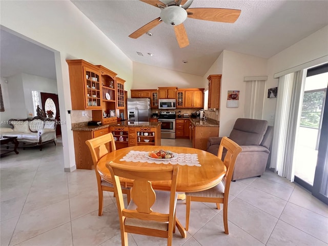 dining space with vaulted ceiling, a textured ceiling, light tile patterned floors, and ceiling fan