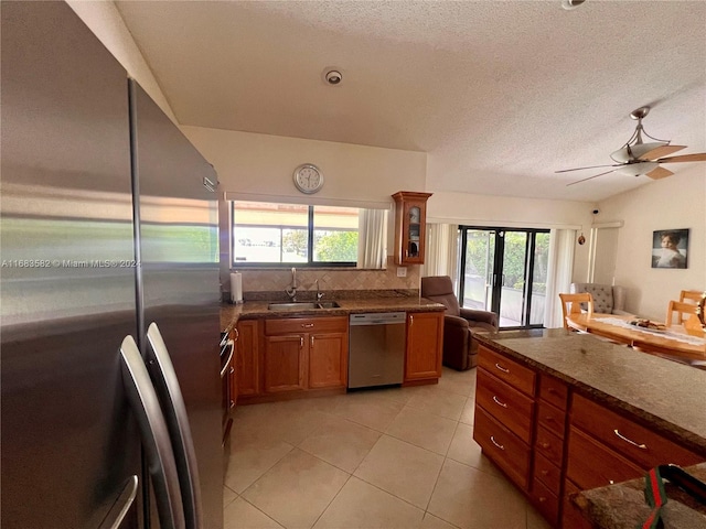 kitchen featuring lofted ceiling, dark stone countertops, sink, appliances with stainless steel finishes, and a textured ceiling