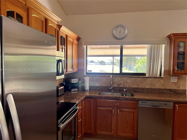 kitchen with sink, decorative backsplash, stainless steel appliances, and dark stone countertops