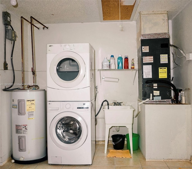 clothes washing area with stacked washer / dryer, a textured ceiling, electric water heater, and light tile patterned flooring