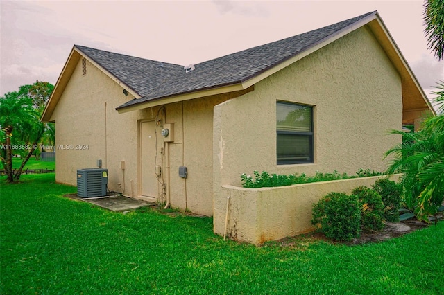 property exterior at dusk featuring a yard and cooling unit