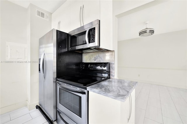 kitchen featuring white cabinets, light tile patterned floors, stainless steel appliances, and tasteful backsplash