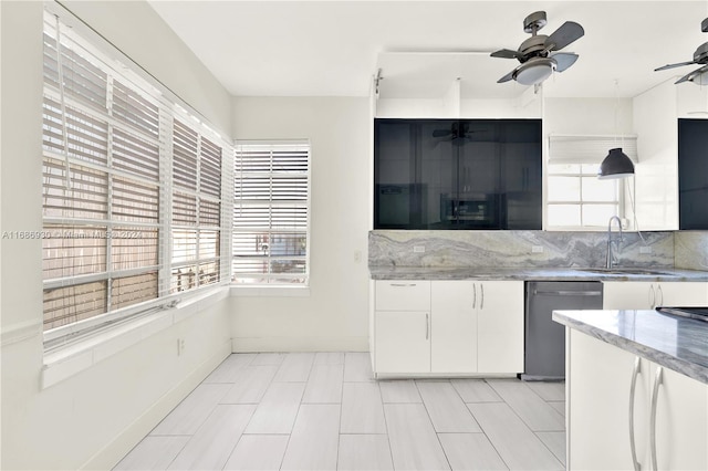 kitchen featuring light stone countertops, white cabinetry, sink, ceiling fan, and stainless steel dishwasher