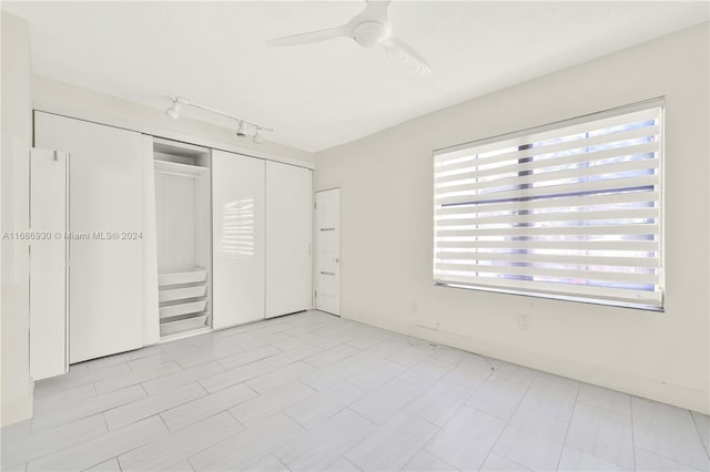 unfurnished bedroom with a closet, track lighting, multiple windows, and ceiling fan